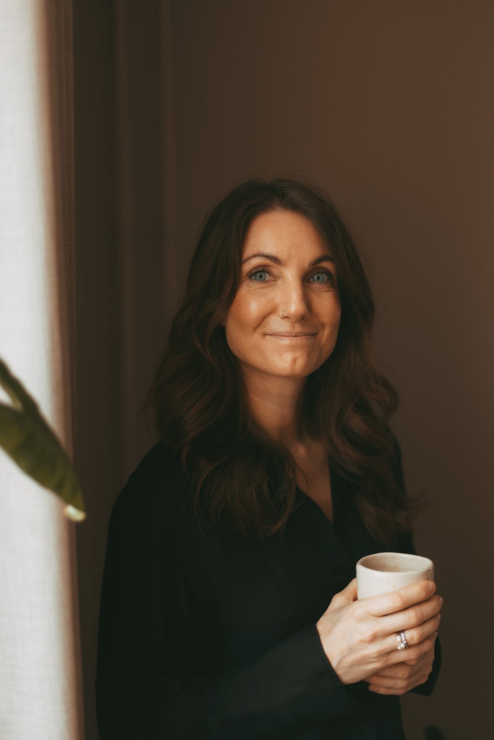 Bettina Spendrup Graulund smiler med en kop kaffe i hånden